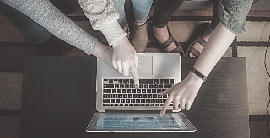 three people looking at the same laptop