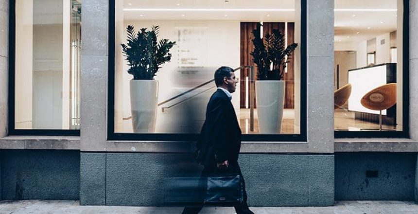 business man walking past a shop window